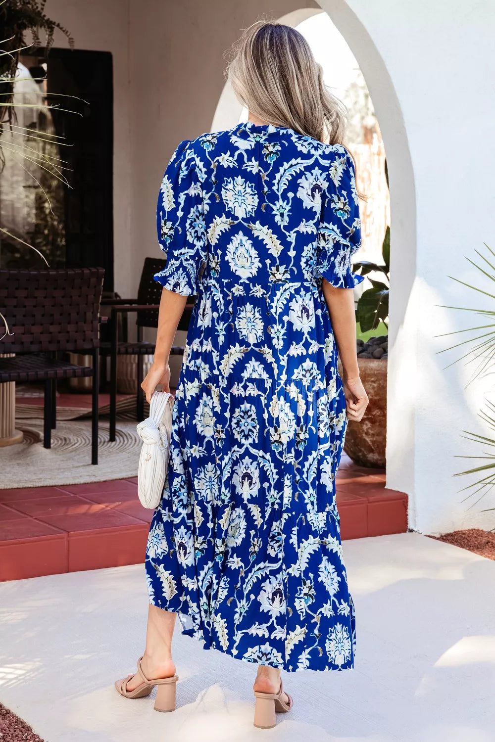 Vibrant floral maxi dress with frilled collar, buttoned front, and tiered skirt.