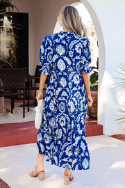 Vibrant floral maxi dress with frilled collar, buttoned front, and tiered skirt.