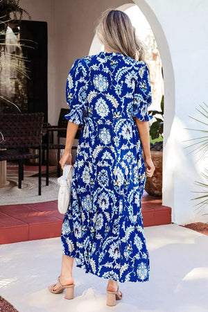 Vibrant floral maxi dress with frilled collar, buttoned front, and tiered skirt.