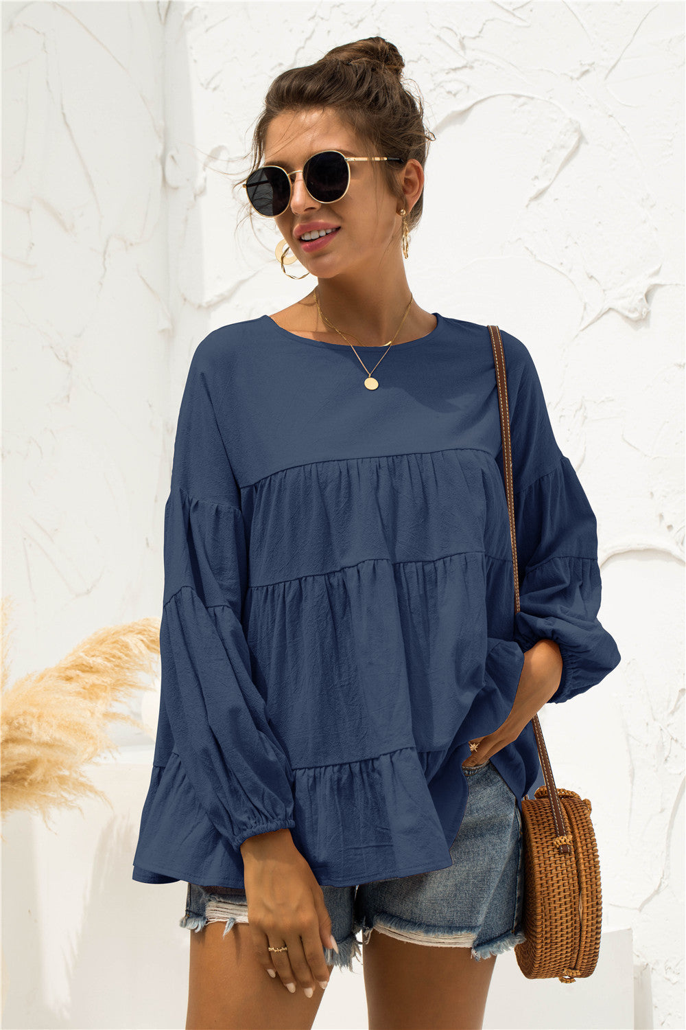 Navy tiered peasant blouse with ruffled bubble sleeves and a round neckline.