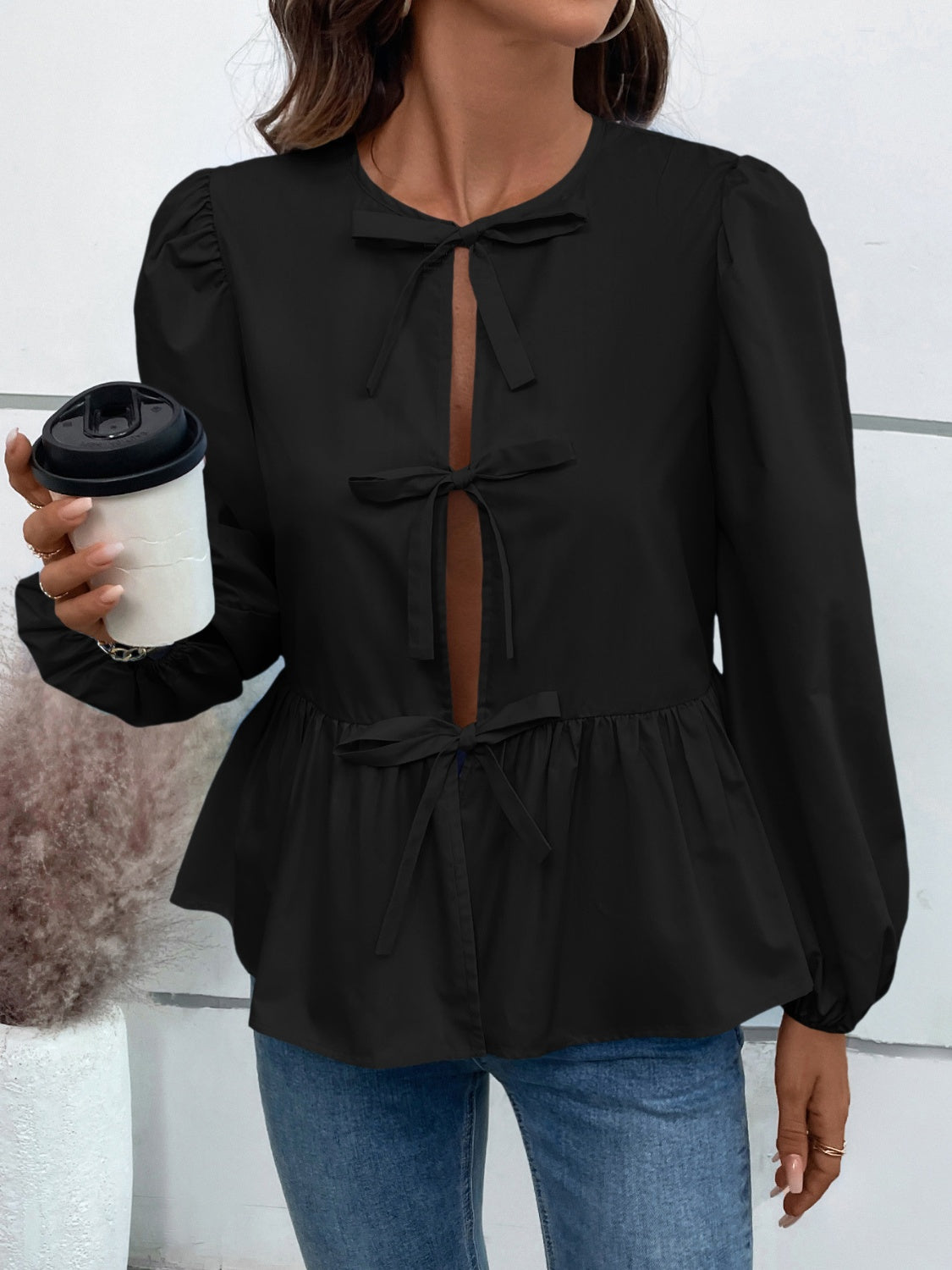 Black peplum blouse with keyhole neckline and bow details.