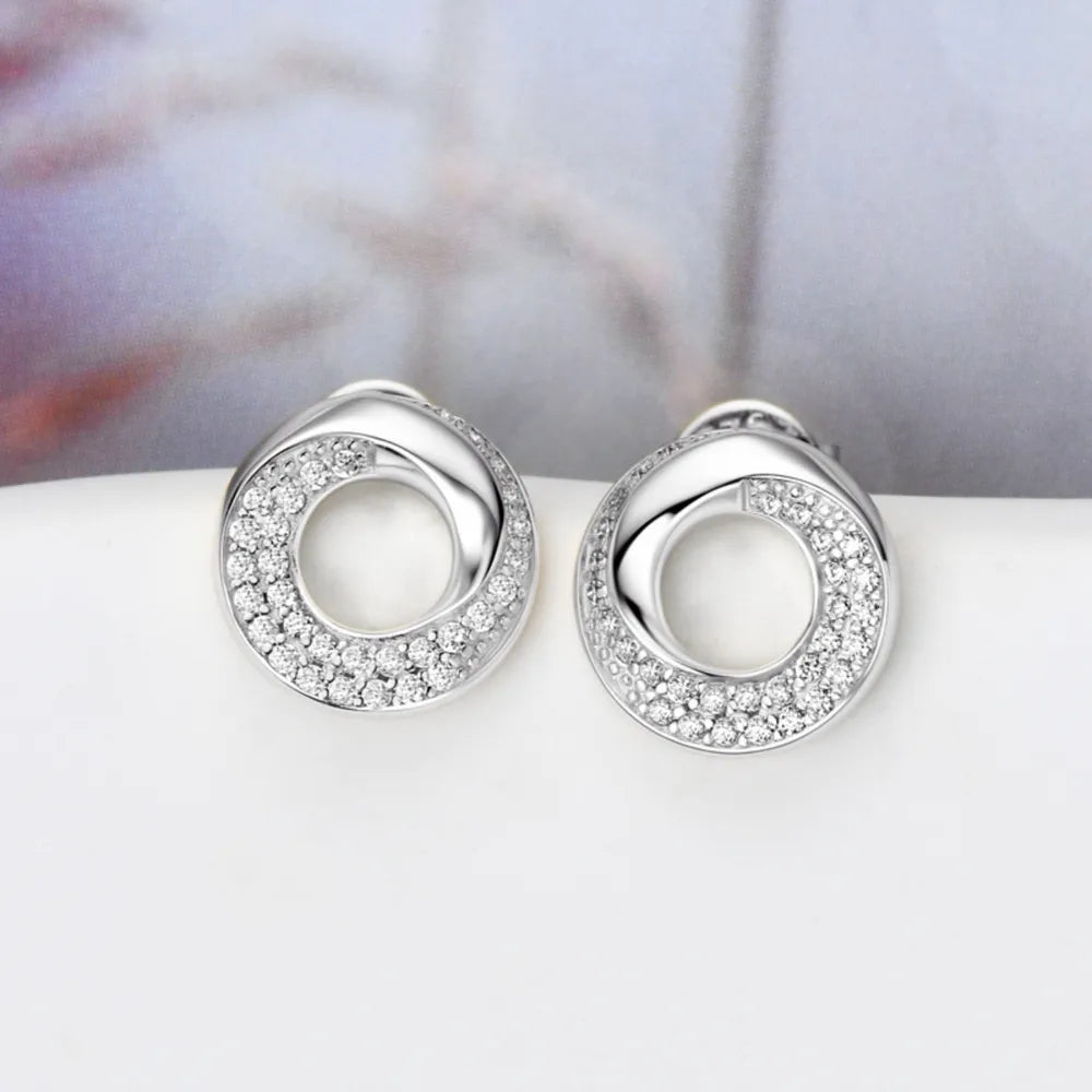 Silver pavé circle stud earrings with a twisted design and sparkling stones.
