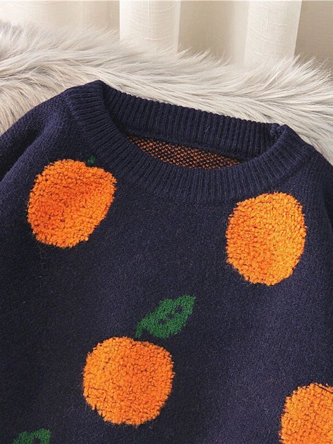 Navy acrylic knit sweater with orange pom-pom fruit pattern and green leaves.