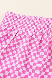 Pink checkered shorts with elastic waistband and drawstring detail.