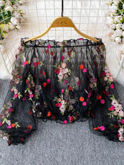 Black off-shoulder t-shirt with embroidered floral detail and ruffled neckline.