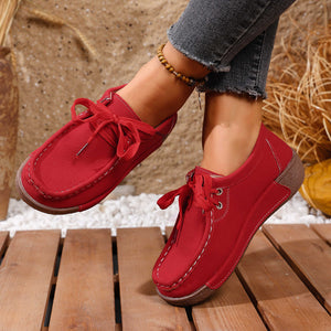 Red lace-up moccasin style sneakers with white stitching detail and brown sole.