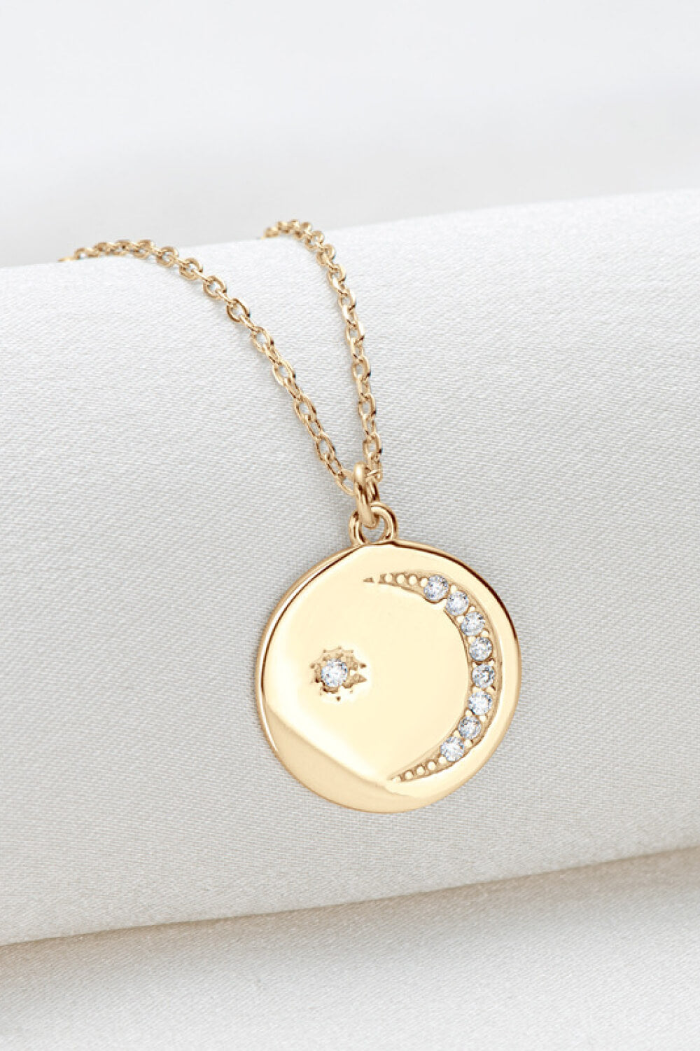 Gold celestial pendant necklace with moon and star charms and crystal accents.
