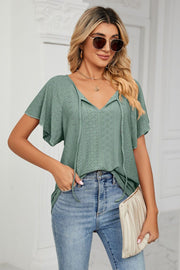 Green eyelet tie-neck blouse with flutter sleeves and V-neck detail