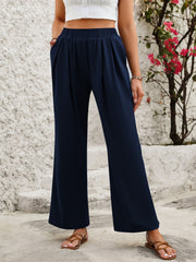 Navy wide leg trousers with elastic waist and pleats, styled with sandals.