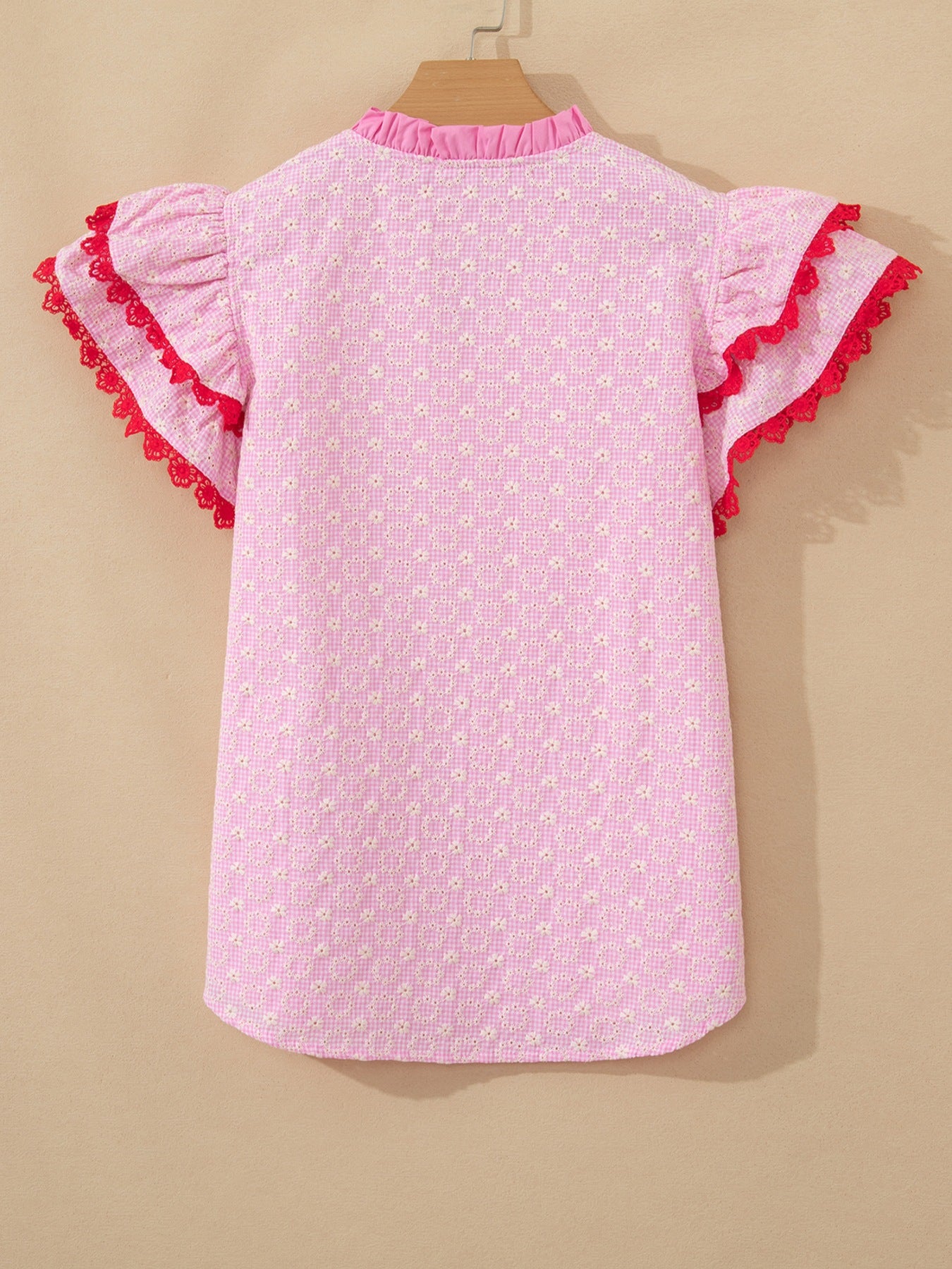 Pink eyelet embroidered blouse with flutter sleeves and red lace trim.