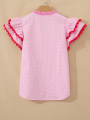 Pink eyelet embroidered blouse with flutter sleeves and red lace trim.