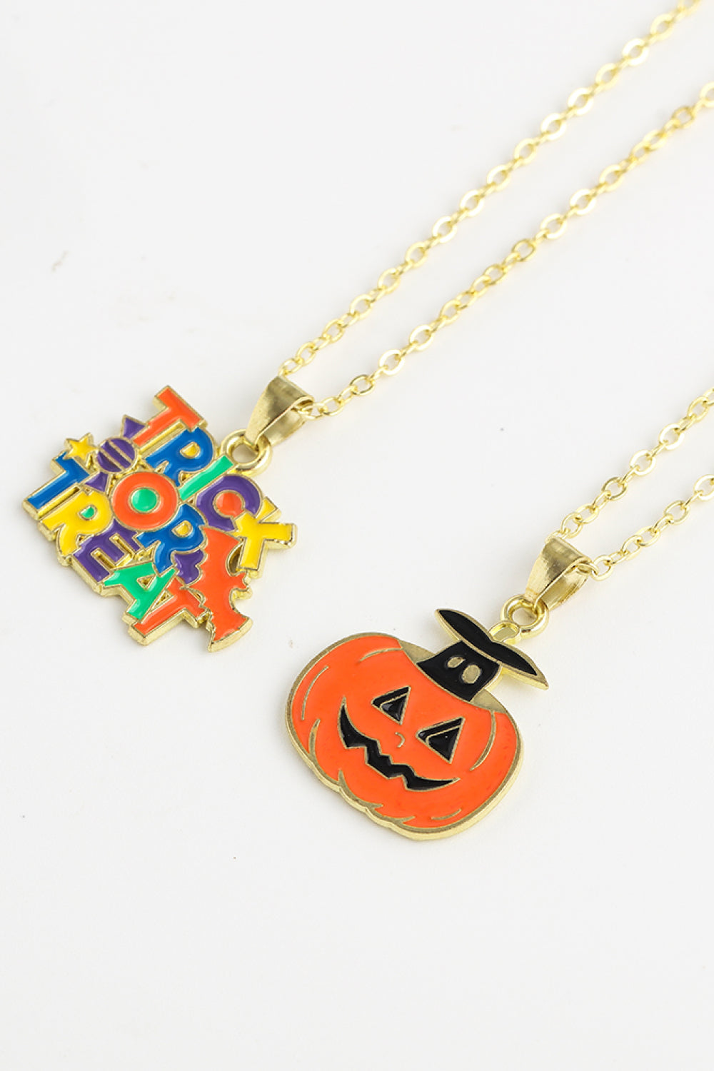 Spooky Season enamel pendant necklaces, one with colorful "Trick or Treat" text, one with a jack-o-lantern.