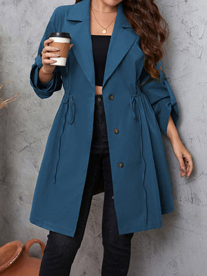 Dusty blue trench coat with gathered waistline and roll-up sleeves.