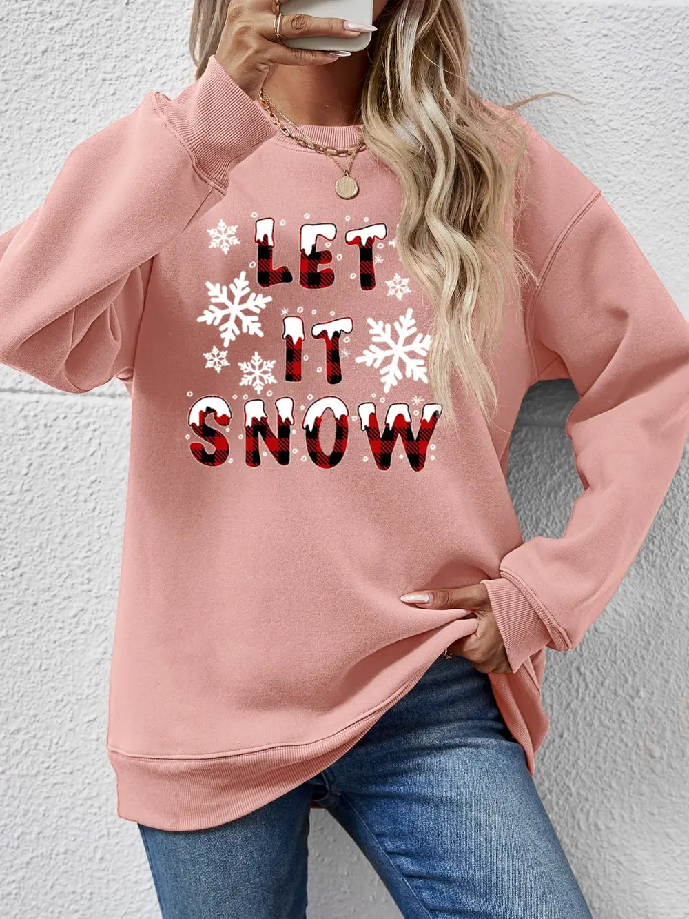 Blush pink crewneck sweatshirt with "Let It Snow" graphic and snowflakes.