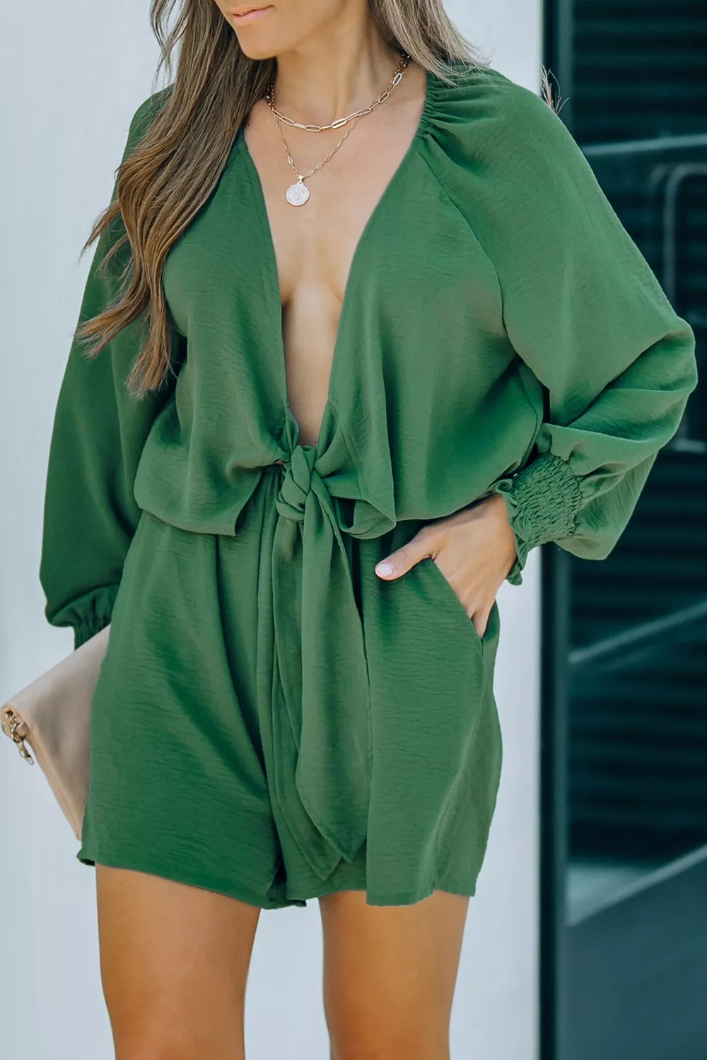 Tie knot puff sleeve romper in dark green with cinched cuffs and a deep V-neck.