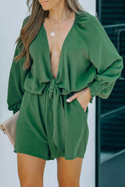 Tie knot puff sleeve romper in dark green with cinched cuffs and a deep V-neck.