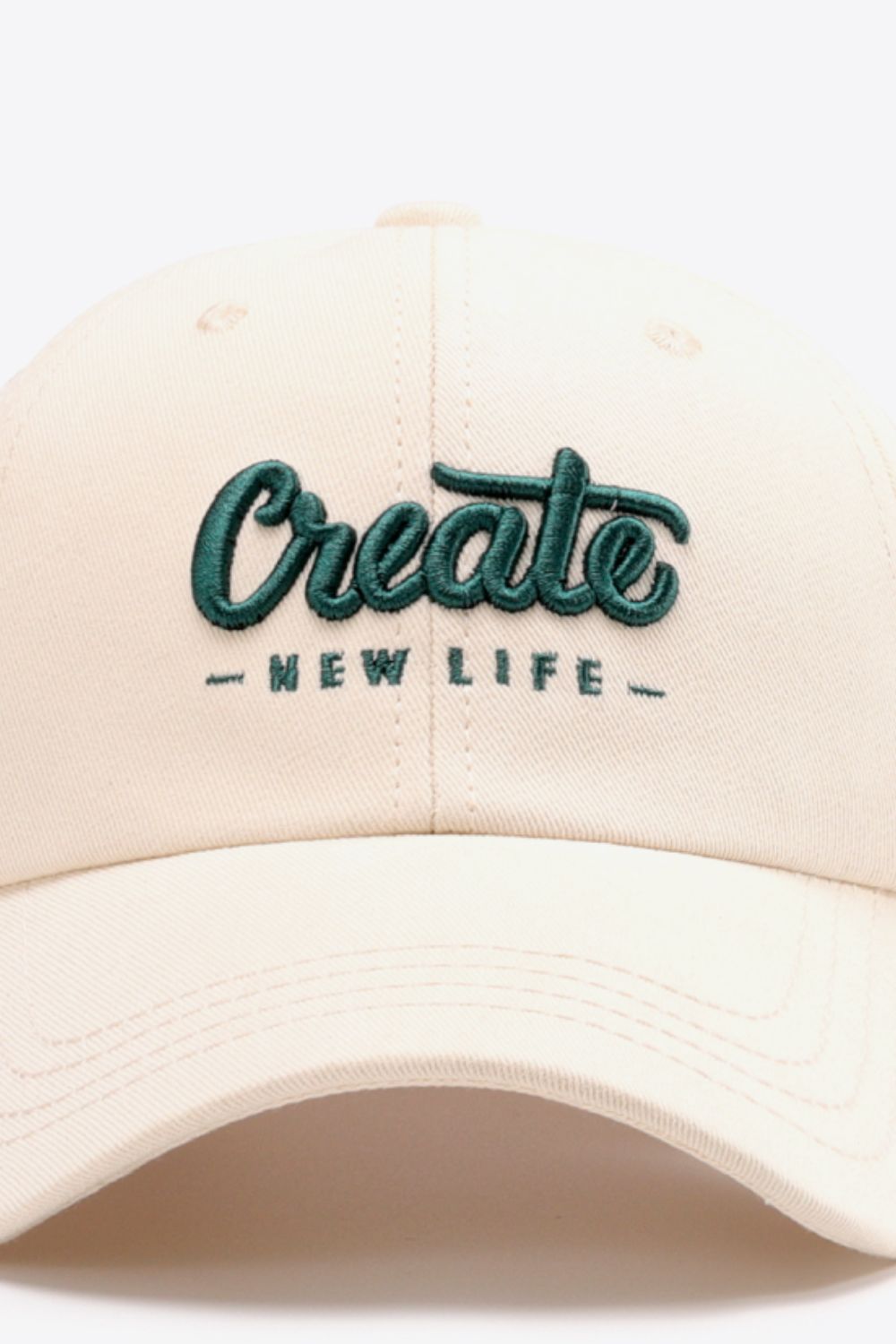 Ivory baseball cap with green embroidered "Create New Life" text.