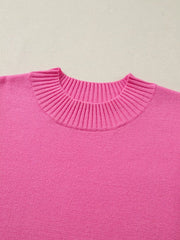Pink knit top with ruffled mock neck and relaxed fit.