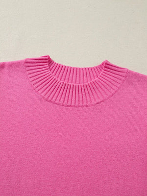 Pink knit top with ruffled mock neck and relaxed fit.
