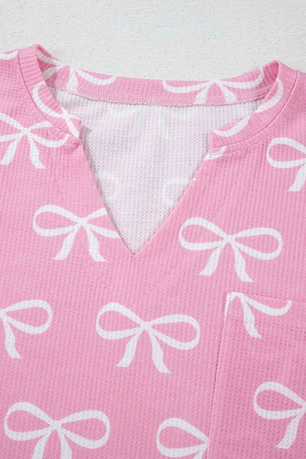 Pink ribbed lounge set with white bow print and V-neck detail.