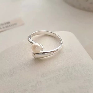 Silver bypass ring with a single luminous pearl accent.