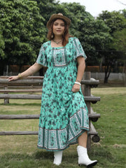Floral maxi dress with square neck, short sleeves, and tiered skirt in green with floral print.