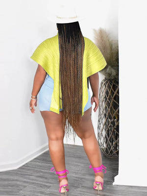Yellow oversized cape shirt with abstract print, polyester, worn with denim shorts and pink heels.