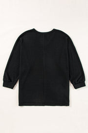 Black waffle knit V-neck top with long sleeves and a slit hem.