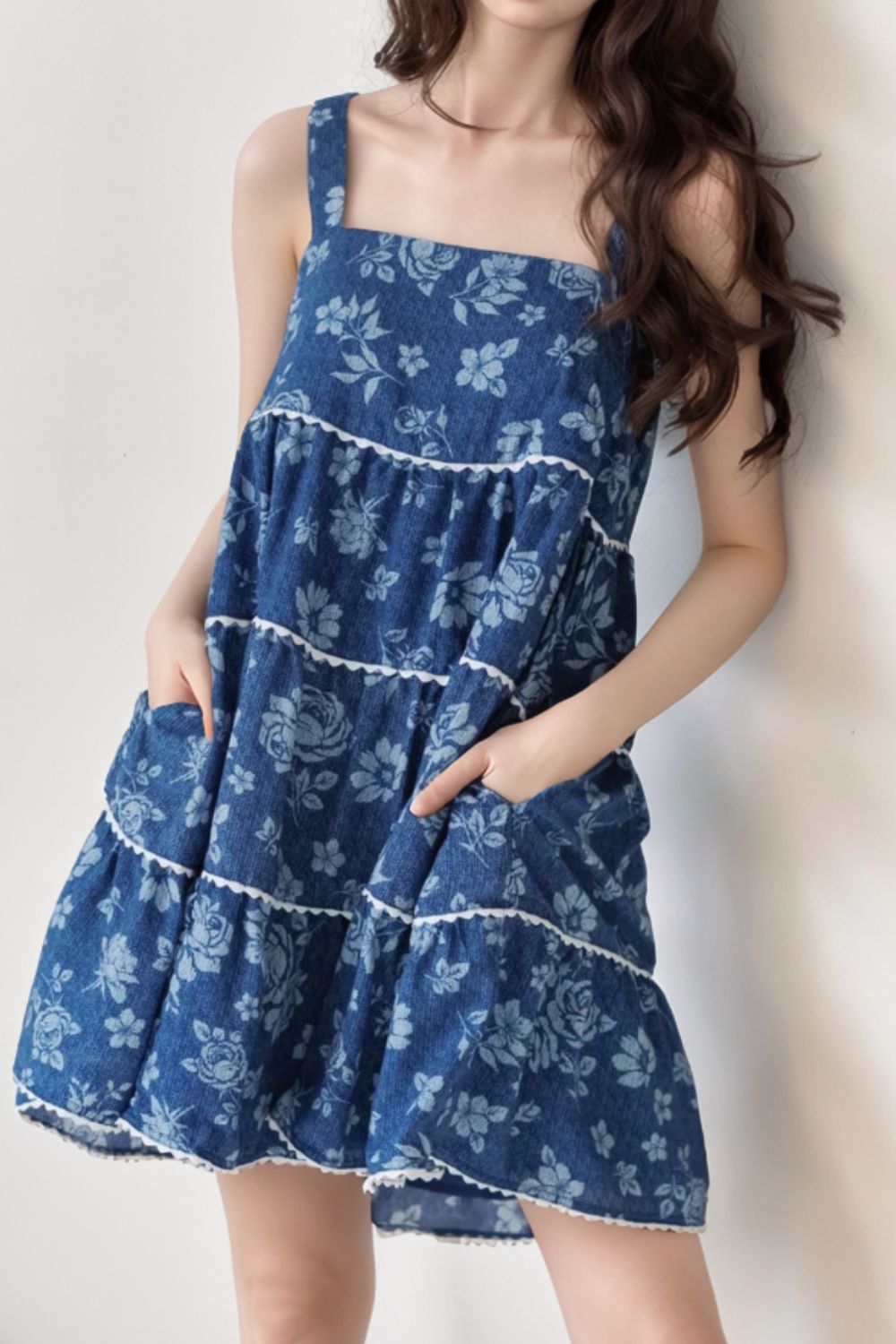 Floral denim sundress with pockets and tiered skirt in medium wash cotton.
