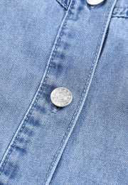 Light blue denim shirtdress with button detail and visible stitching.