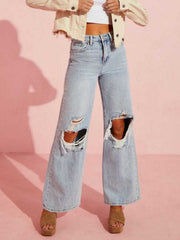 Light wash denim wide leg jeans with distressed knee rips and a flare hem.