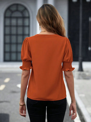 Orange blouse with shirred short sleeves and a V-neckline.