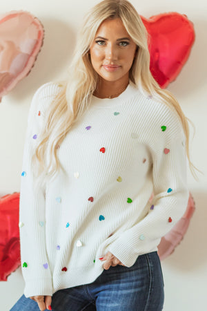 White ribbed knit sweater with colorful heart embellishments.