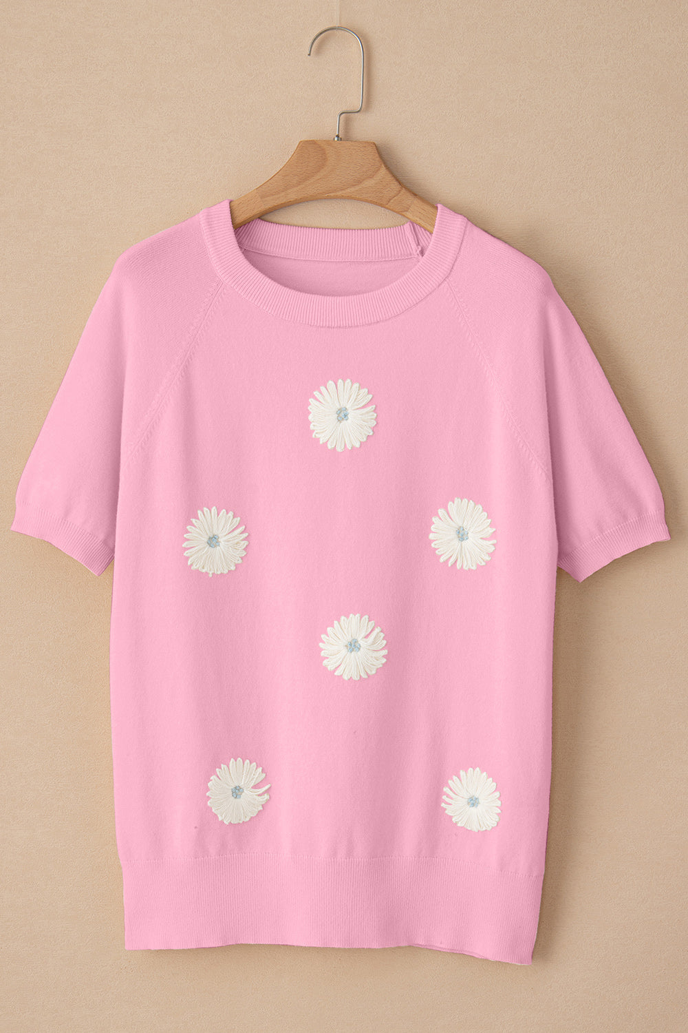 Pink knit top with daisy appliqués, crew neck, and short sleeves.