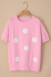 Pink knit top with daisy appliqués, crew neck, and short sleeves.