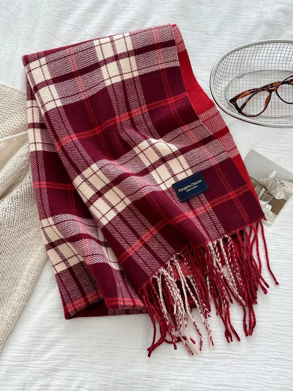 Red plaid scarf with fringe and a classic pattern.