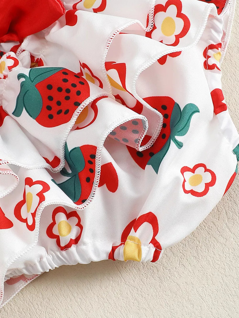 Baby set with strawberry and flower print, featuring ruffles and a white fabric.