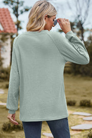 Light green waffle knit raglan sleeve top with eyelet detail on sleeves.