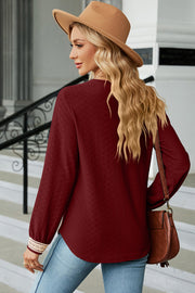 Burgundy textured V-neck blouse with lace trim cuffs and long sleeves.