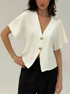 White asymmetrical V-neck buttoned shirt with short sleeves and gold buttons.