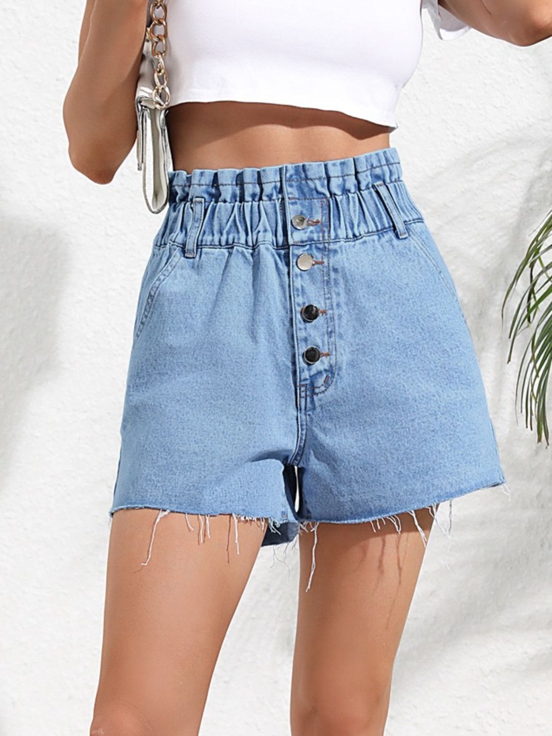High-waisted denim paperbag shorts in medium wash with button fly and frayed hem.