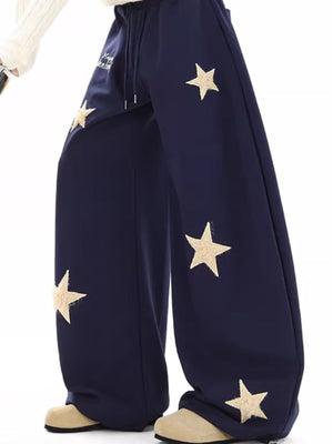 Navy wide leg sweatpants with drawstring and scattered star appliques.