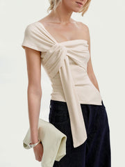 Beige asymmetrical t-shirt with knot detail and ruched sides, styled with dark denim.