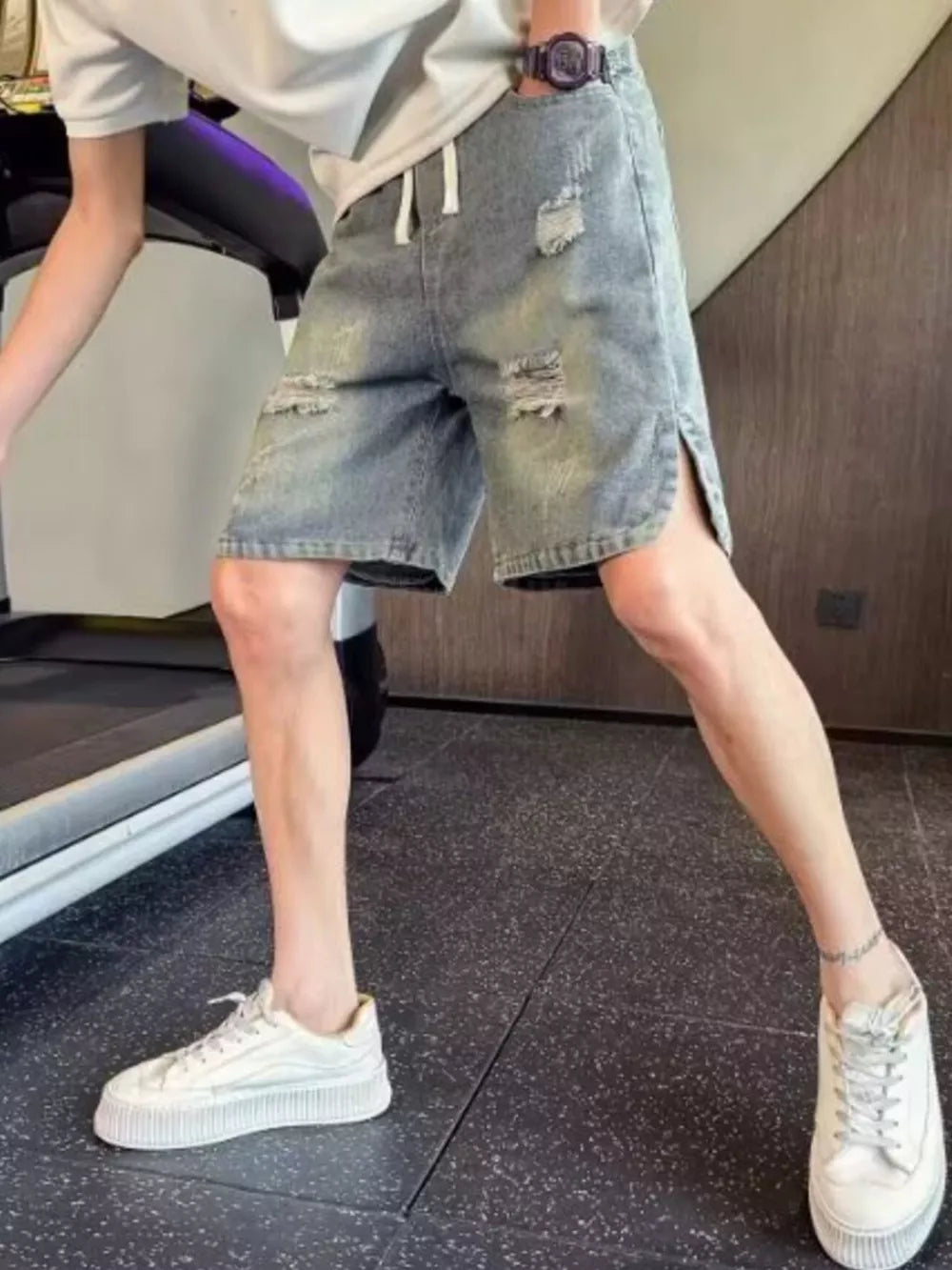 Distressed denim shorts with adjustable drawstring, side slits, and raw hem.