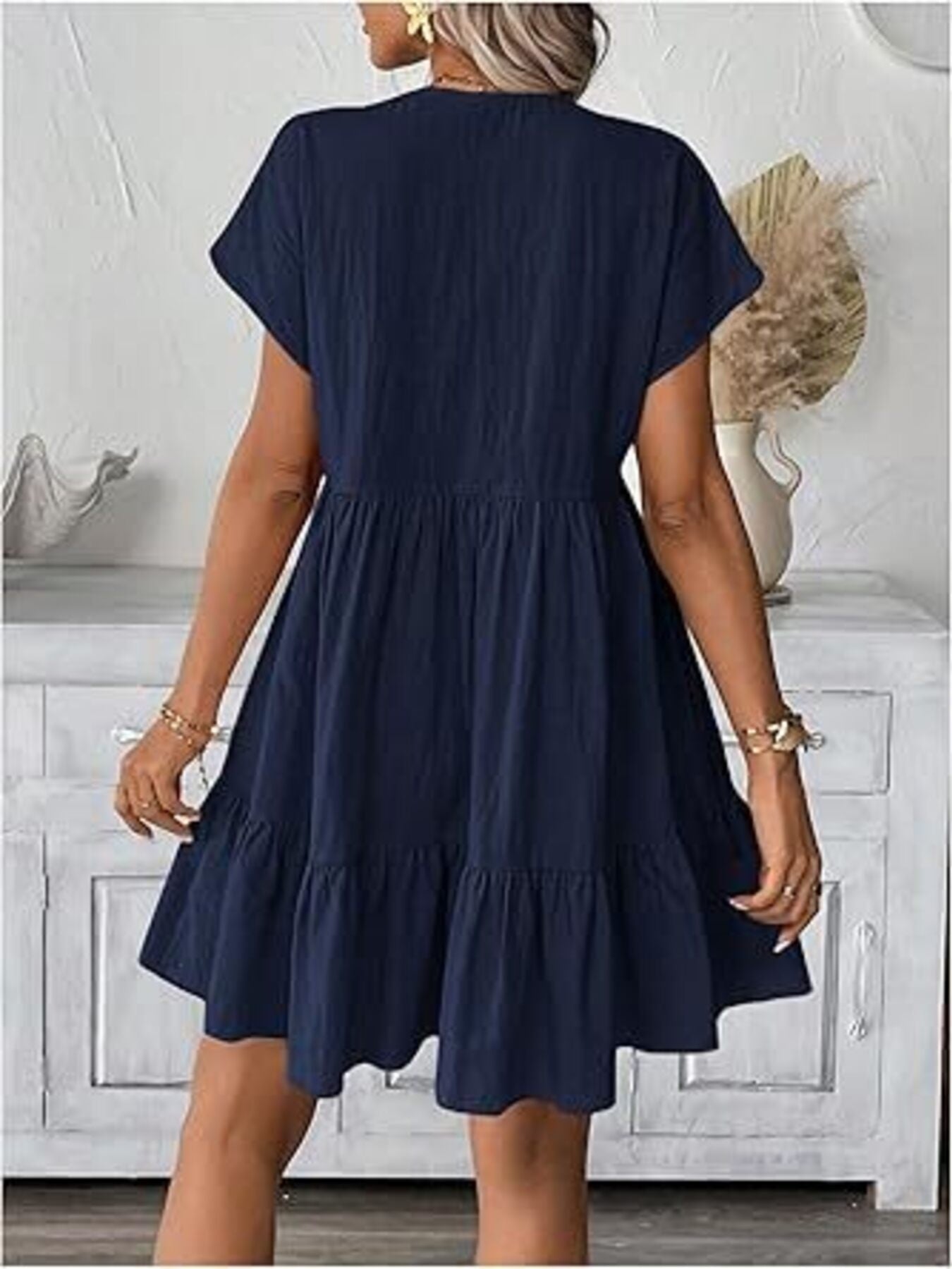 Navy ruffled mini dress with short sleeves and V-neck, tiered skirt detail.