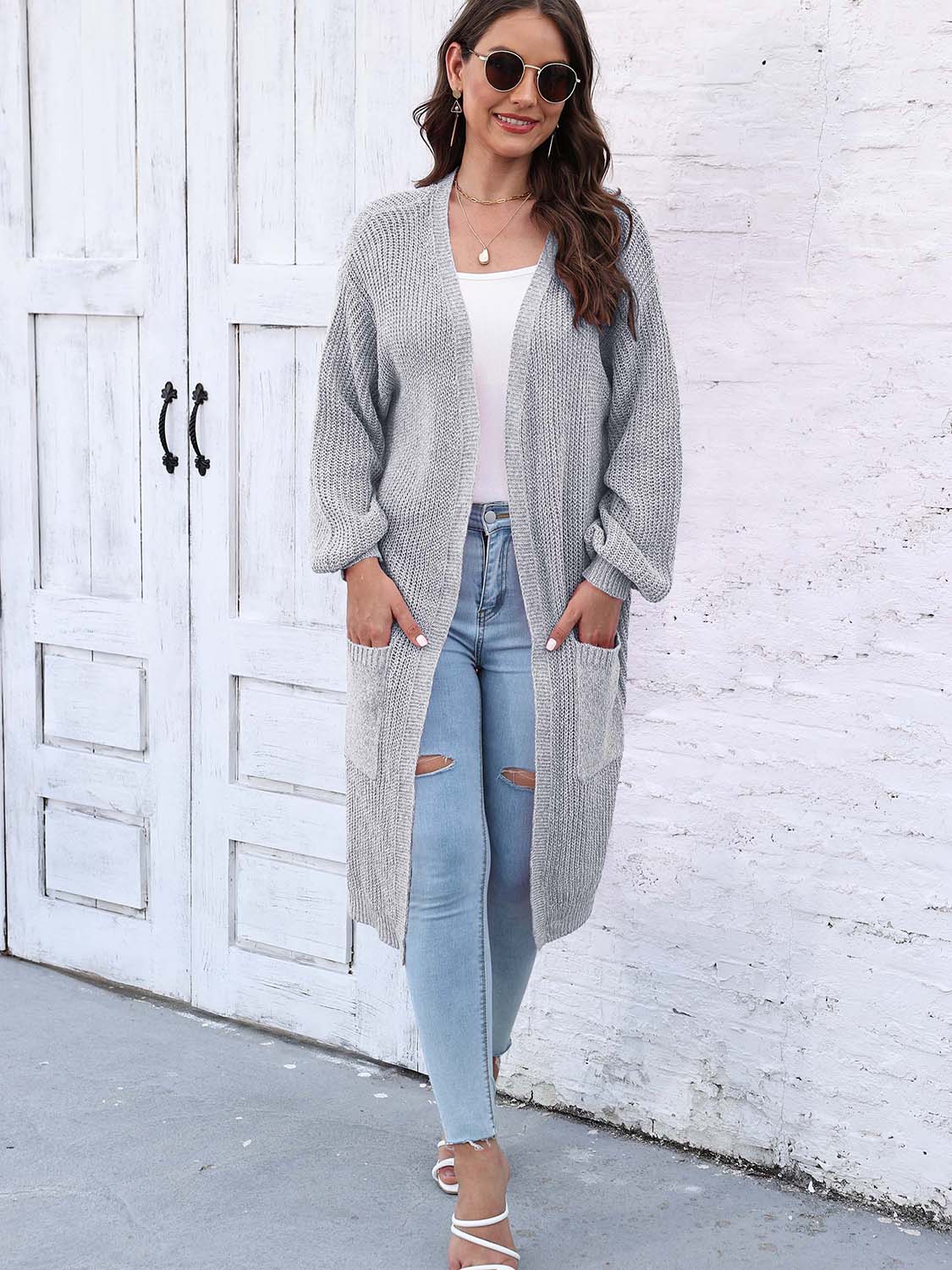 Charcoal ribbed knit maxi cardigan with pockets and balloon sleeves, worn open over a white top and ripped jeans.