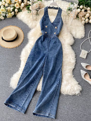 Blue denim halter neck wide-leg jumpsuit with gold buttons and V-neck.