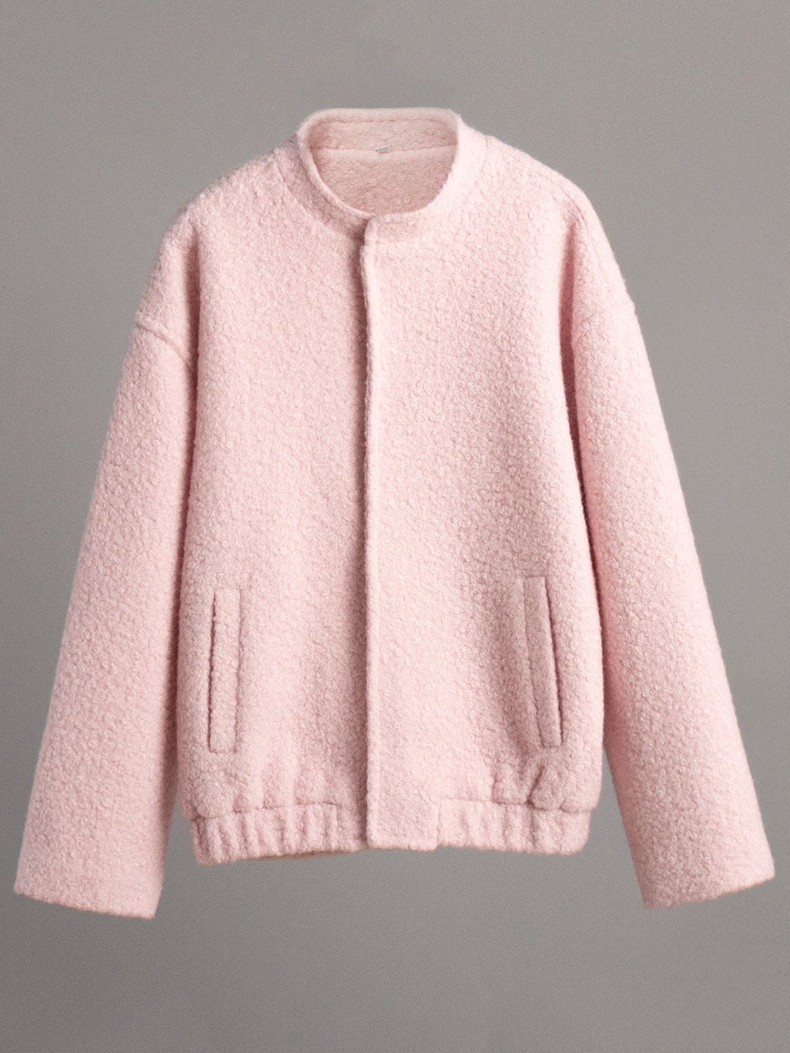 Blush pink textured bouclé bomber jacket with rounded neck and elastic cuffs.