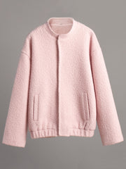 Blush pink textured bouclé bomber jacket with rounded neck and elastic cuffs.