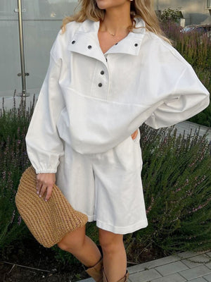 White two-piece set with snap details and shorts, styled with a straw clutch.